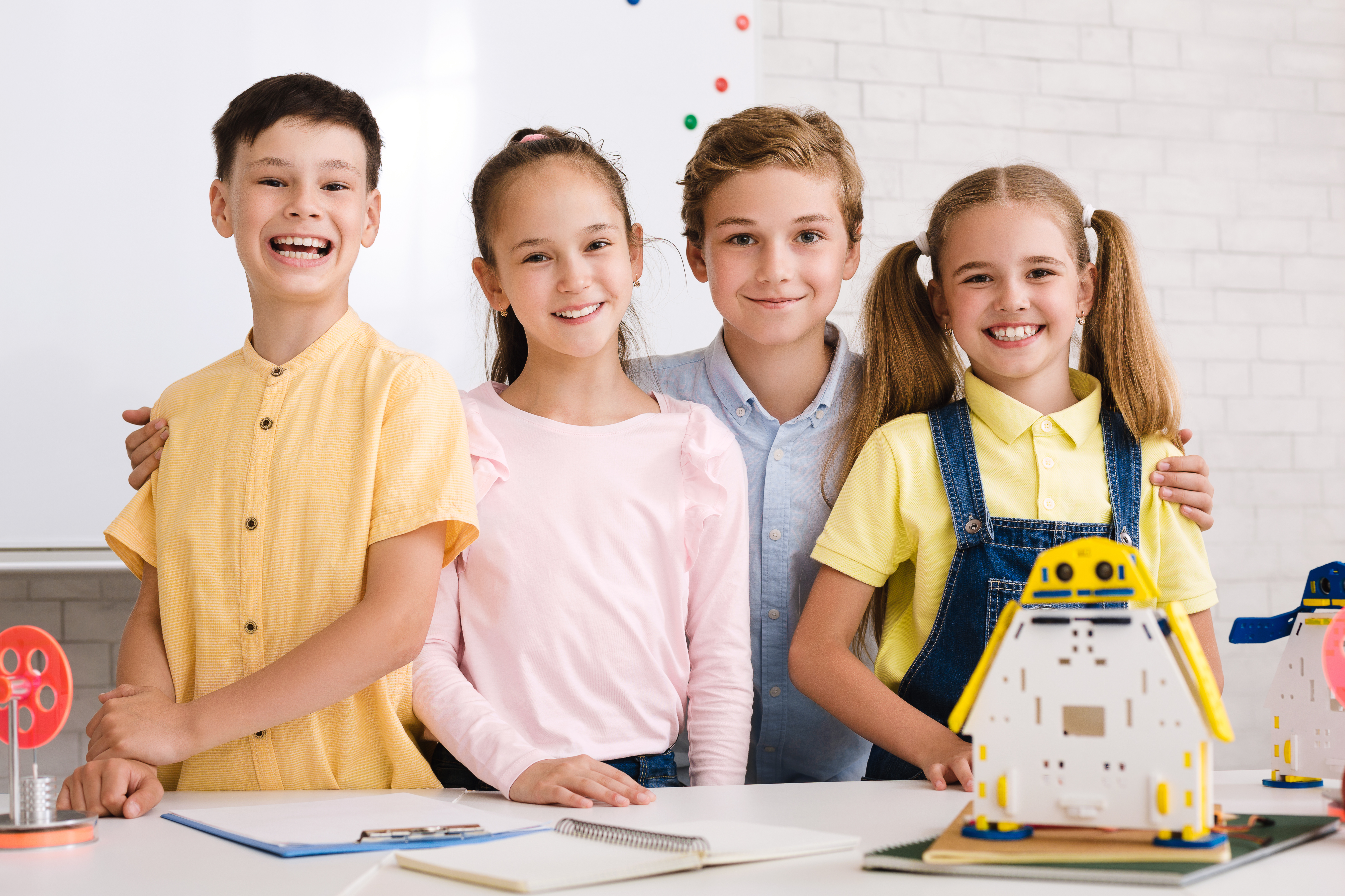 Portrait of pupils building robots in after school stem class, smiling to camera together